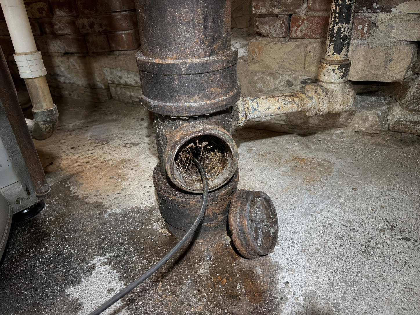 Aging sewer cleanout and cast iron plumbing in an Independence home basement